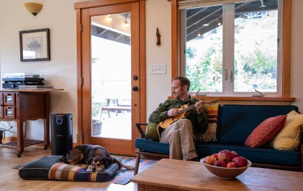 Man enjoying time with his dog next to an air purifier.