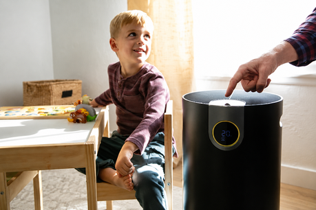 Child at table playing while parent turns on an air purifier